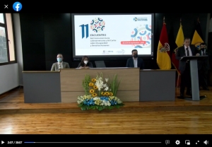 Captura de pantalla de la transmisión de la apertura. Se observan personas detrás de una mesa larga dispuesta para los oradores, también a un hombre de pie detrás de un atril. Como imagen de fondo se encuentra una pantalla gigante con la imagen institucional del 11vo. encuentro